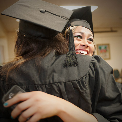Two graduating students hugging.