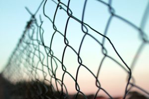 a chainlink fence in front of a sunrise