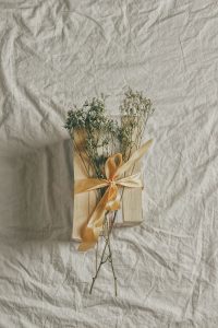 four books and some flowers wrapped in a ribbon