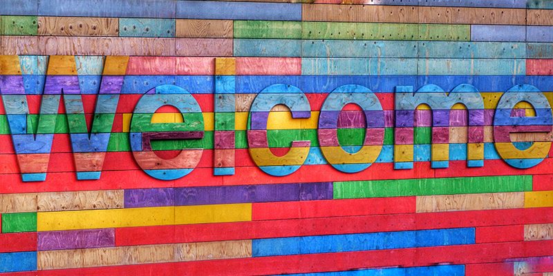 colorful pieces of wood spell "Welcome" on a colorful backround