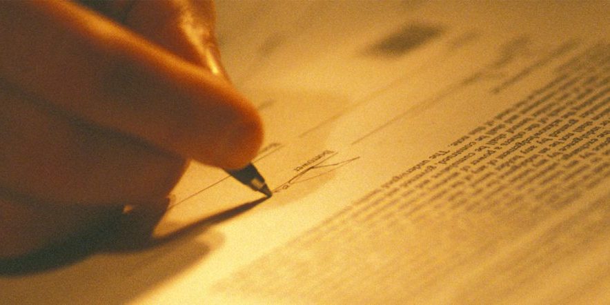 a hand signing a document