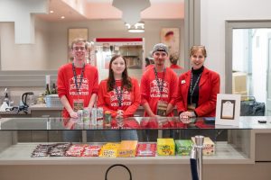 four people in red shirts standing behind a concession stand in a movie theater