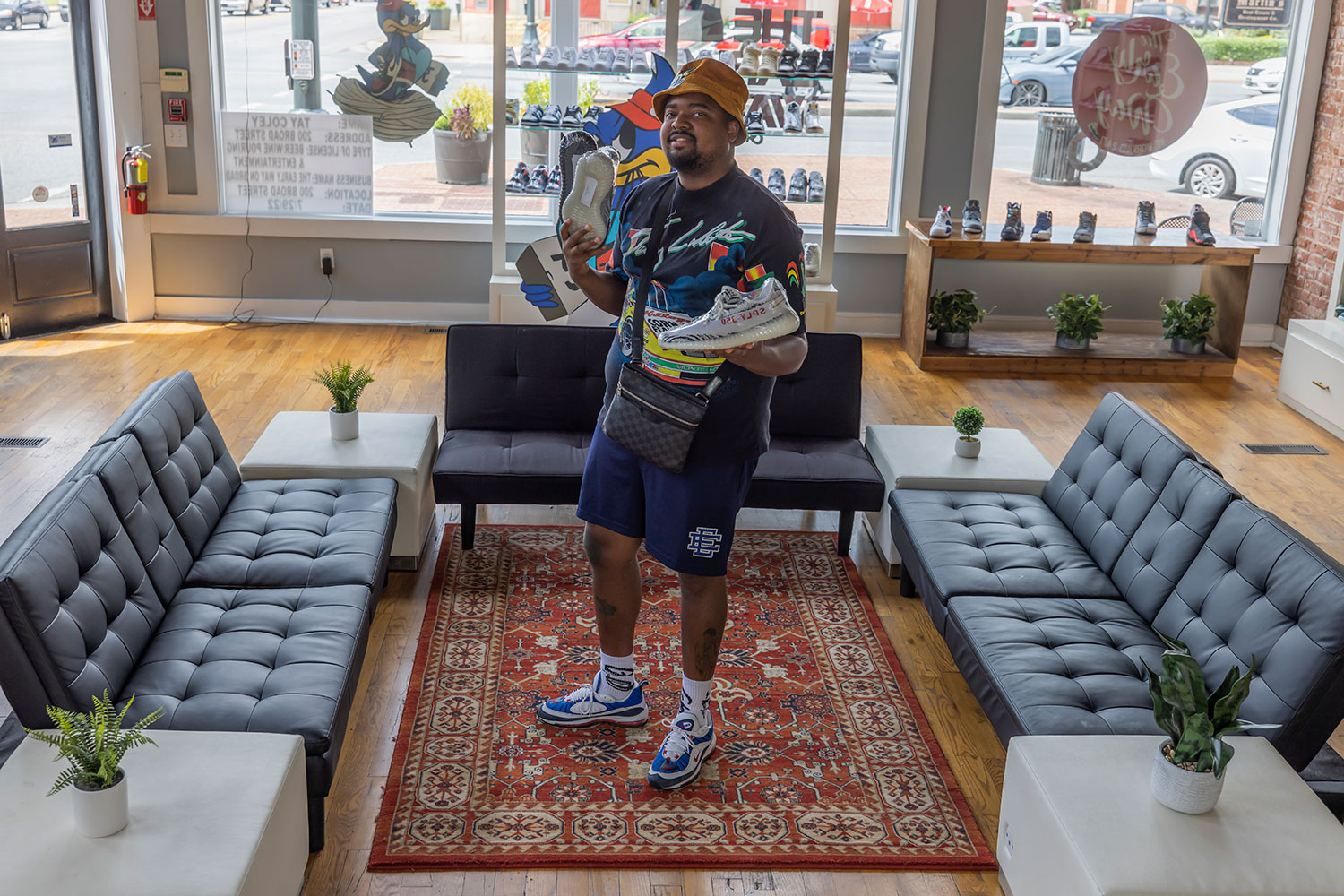 Rontavious “Tay” Coley holds up a pair of shoes in his new store