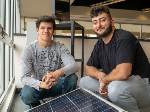 Jayem Odeh and Spencer Bush sitting beside a row of solar panels