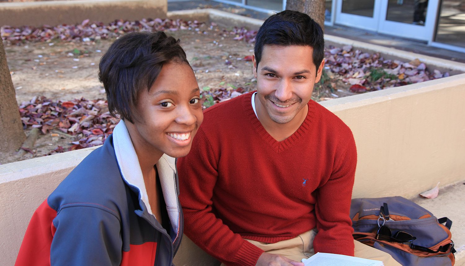 Photo of two students sitting on a bench.