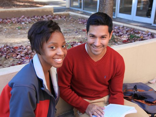 Photo of two students sitting on a bench.