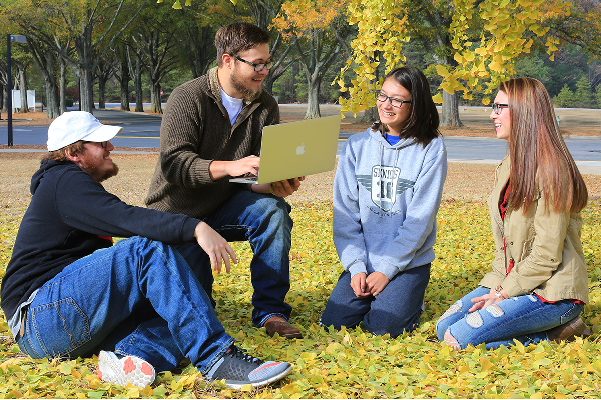 Students sitting outside on the grass.