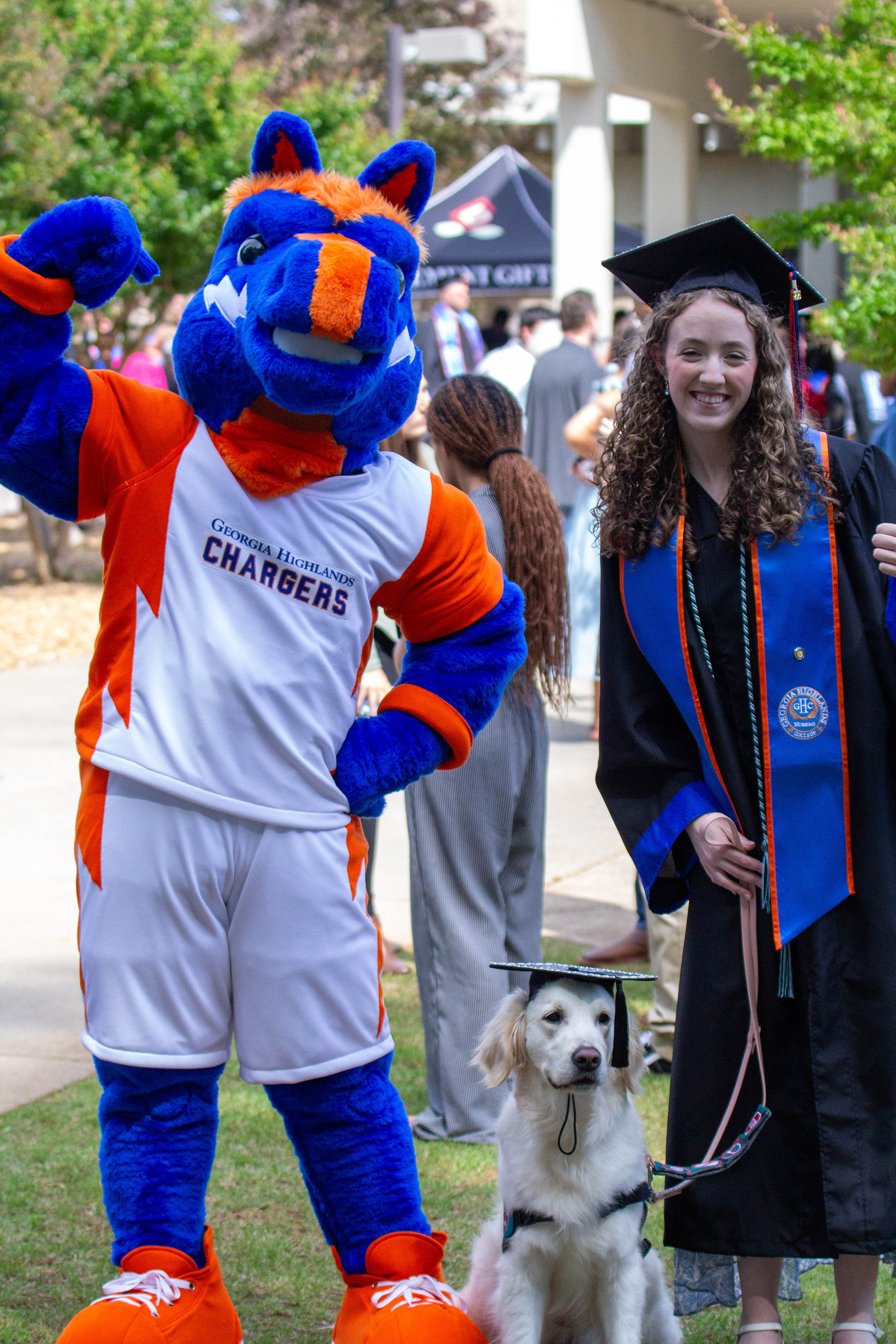 GHC mascot Bolt with a graduate and her service dog