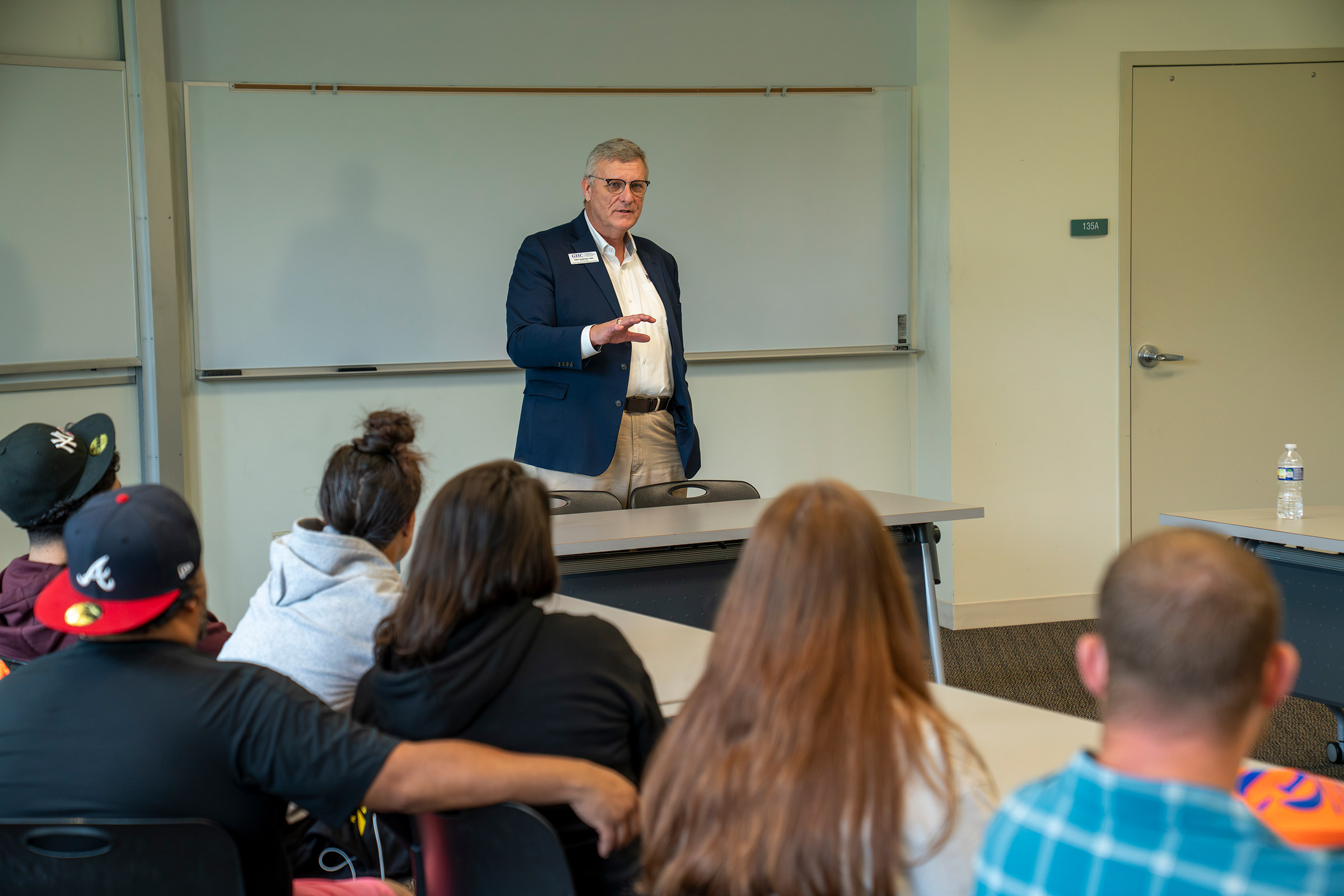 Image of faculty member speaking in a classroom to students.