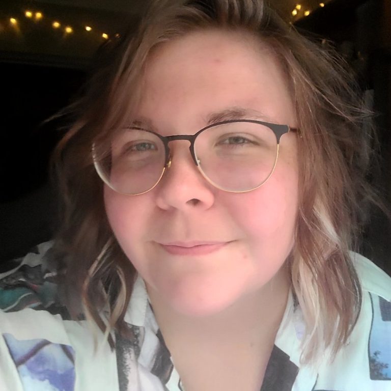 AlyGilmore Woman with shoulder-length hair and glasses smiling