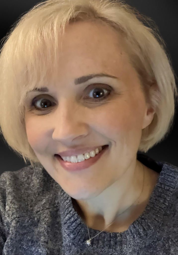 Woman with light colored hair in a bob style smiling with a black background