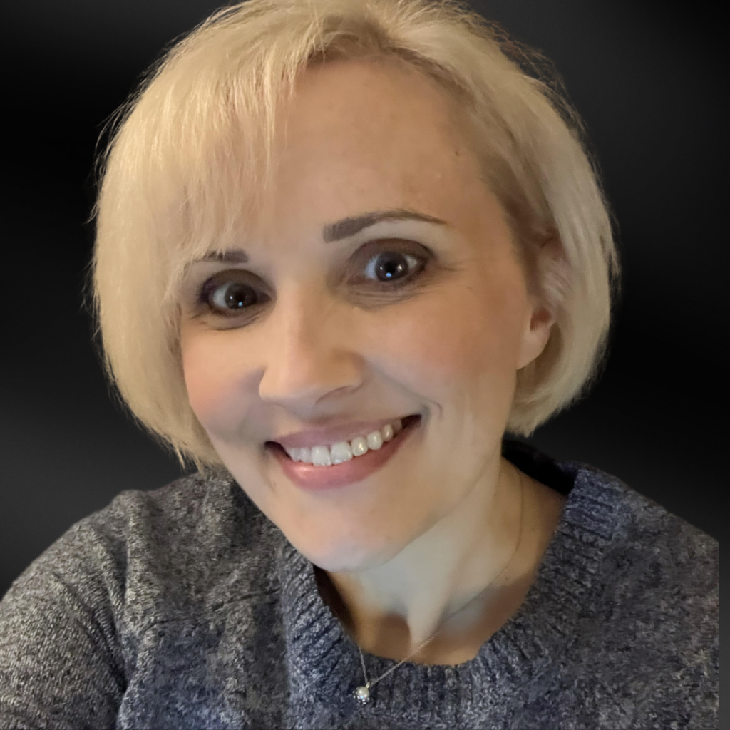JulieKozee Woman with light colored hair in a bob style smiling with a black background