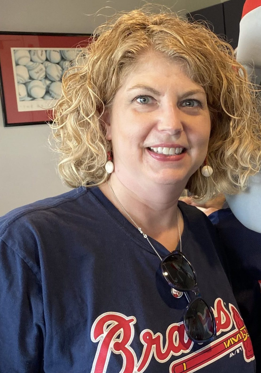 Woman with curly hair smiling, wearing a braves shirt