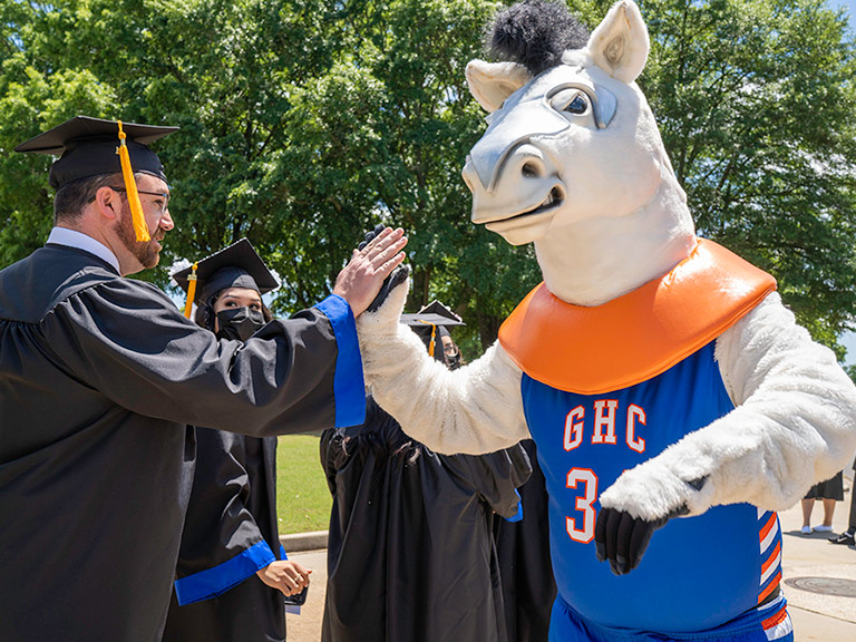 Bolt, GHC's Mascot, high fiving graduating student